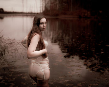 Young woman looking away while standing in lake