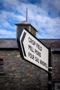 Close-up of information sign by sea against sky