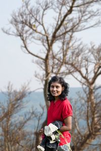 Portrait of smiling boy standing against tree