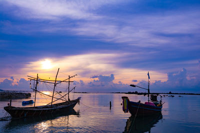 Boats moored in sea against sky during sunset