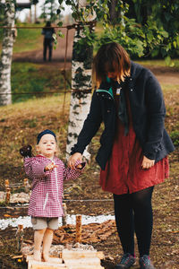 Full length of mother and girl standing outdoors