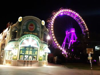 Low angle view of illuminated ferris wheel in city at night