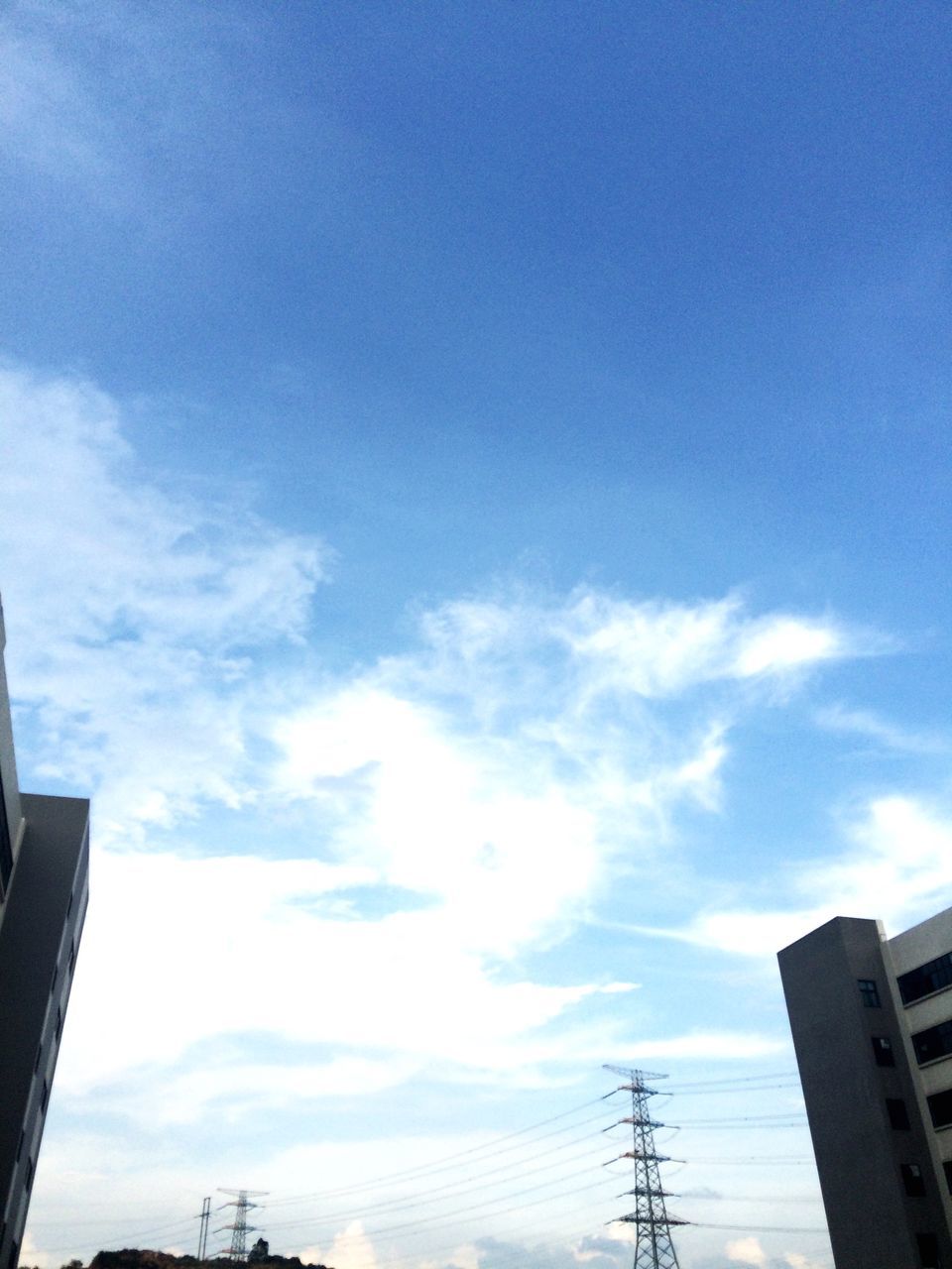 low angle view, architecture, built structure, building exterior, sky, silhouette, cloud - sky, city, cloud, blue, power line, building, outdoors, no people, electricity pylon, high section, cloudy, day, connection, cable