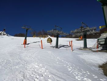 Snow covered field against clear blue sky