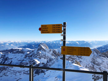 Information sign on snowcapped mountain against sky