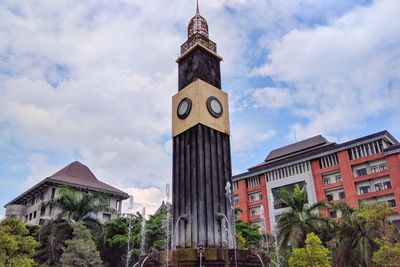 Low angle view of clock tower amidst buildings in city against sky