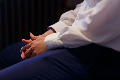 Midsection of well-dressed man sitting in dark