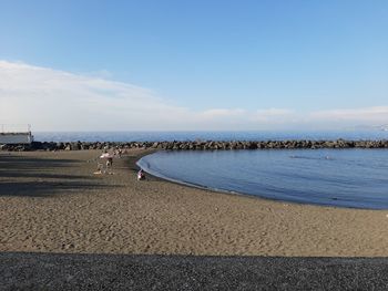 People on beach by sea against sky