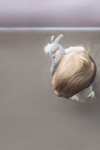 Overhead view of baby girl holding stuffed toy at home