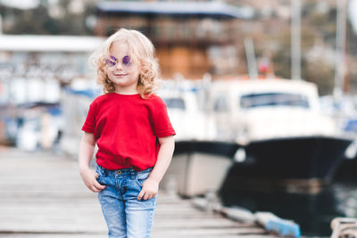 Smiling girl standing with hands in pockets on jetty