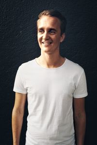 Portrait of smiling man standing against black background