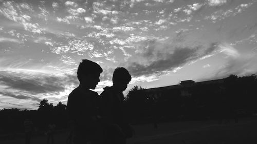 Silhouette father and son against sky during sunset