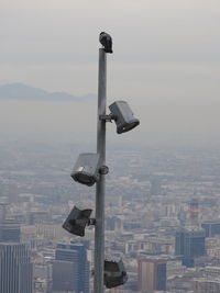 Coin-operated binoculars by cityscape against sky