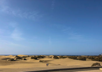 Scenic view of desert against blue sky