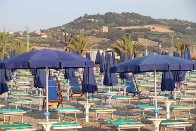 Lounge chairs and tables on beach against sky