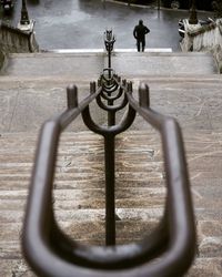 High angle view of metallic railing with man on staircase in city