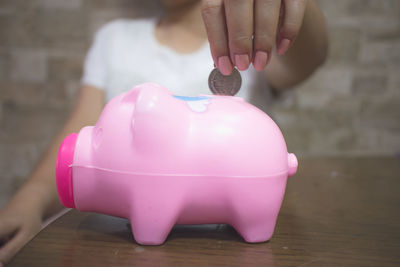 Midsection of woman holding pink flower on table