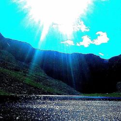 Sun shining through clouds over mountains