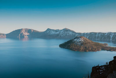 Scenic view of sea and mountains against clear blue sky