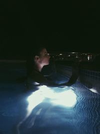 Portrait of young man swimming in pool at night