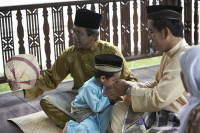 Son kissing hands of father while sitting in gazebo