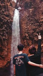 Rear view of man standing by waterfall