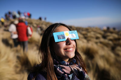 Smiling teenage girl wearing 3-d glasses outdoors