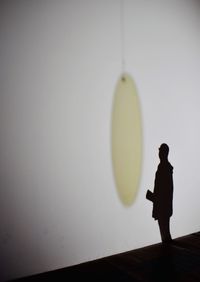 Silhouette boy standing against wall