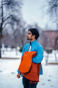 Side view of young woman standing on snow