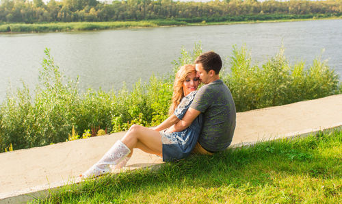 Young couple sitting on grass by lake
