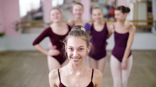 Portrait of a young girl ballet dancer in a lilac ballet leotard, smiling, sending an air kiss