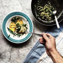 Cropped image of person having spaghetti on table