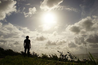 Rear view of silhouette man standing on field against sky