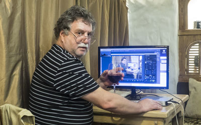 Portrait of man having drink while using computer at home