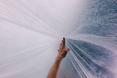 Cropped hand of man reaching spraying water