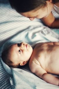 High angle view of mother looking at son lying on bed at home