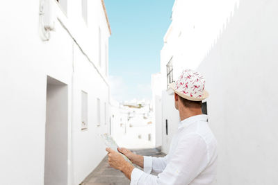 Portrait of woman holding white umbrella against wall