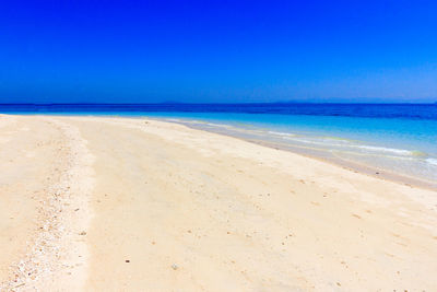 Scenic view of beach against clear blue sky