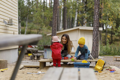 Mother playing with children in sandpit