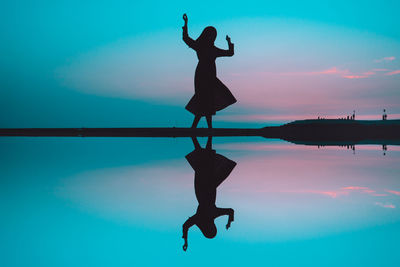Silhouette man jumping in swimming pool against sky during sunset