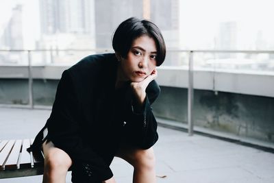 Portrait of young woman wearing suit while sitting on bench