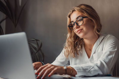 Portrait of young woman using laptop at office