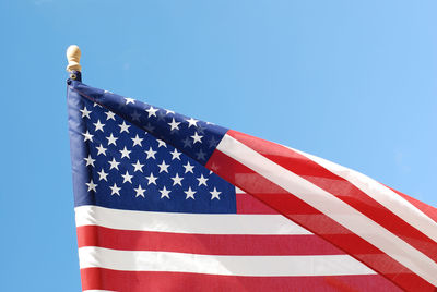 Low angle view of flag against blue sky