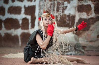 Portrait of young woman against red wall