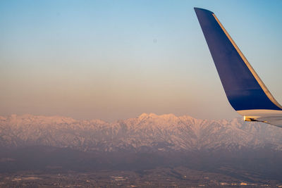 Cropped image of airplane wing against sky during sunset