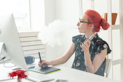 Young woman using mobile phone while sitting on table