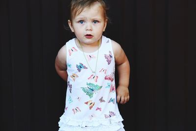 Portrait of baby girl standing against black background