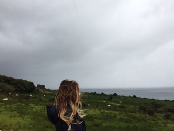 Woman standing at beach against sky