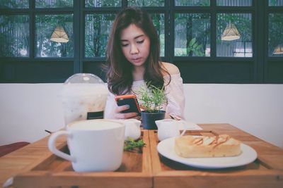 Woman eating food on table in restaurant