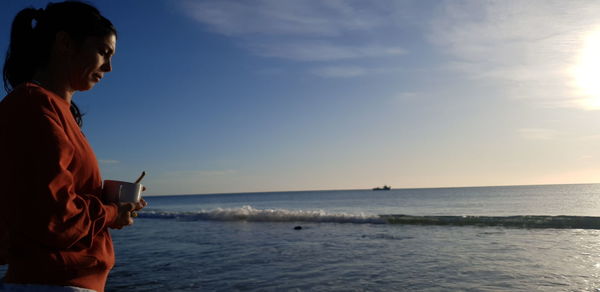 Woman standing on beach against sky